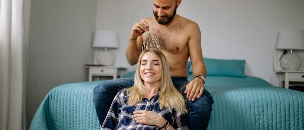 foto van een man die een goed hoofdmassage apparaat uitprobeert op zijn vrouw